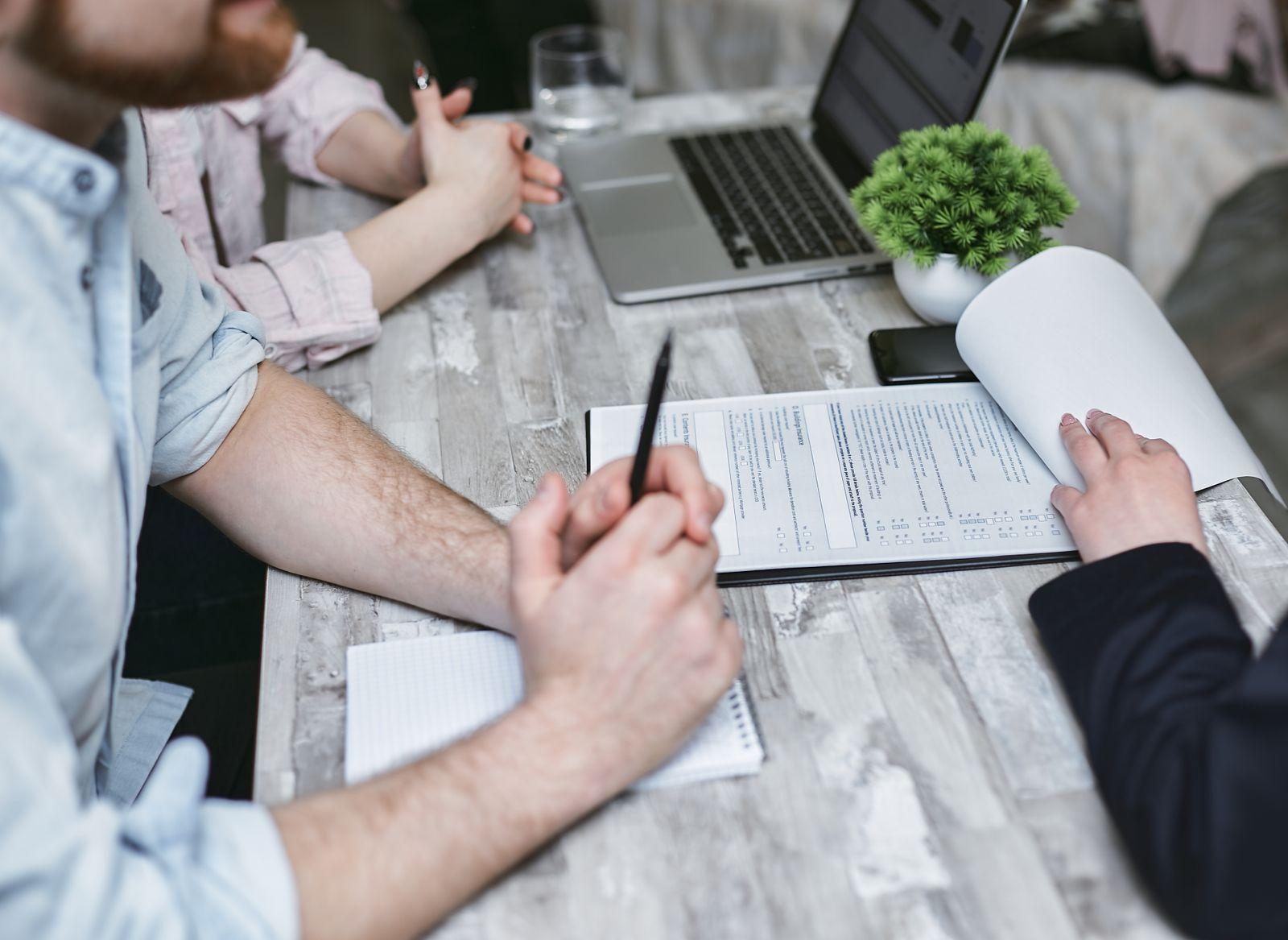 Dos personas revisan un formulario impreso sobre una mesa de trabajo.
